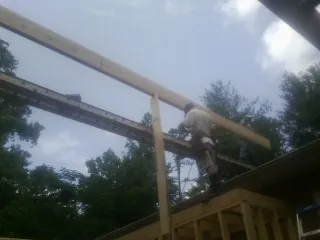 Carpenter setting a ridge beam over a new addition frame — Ice Dam Removal by Roofing Brothers in Waubun