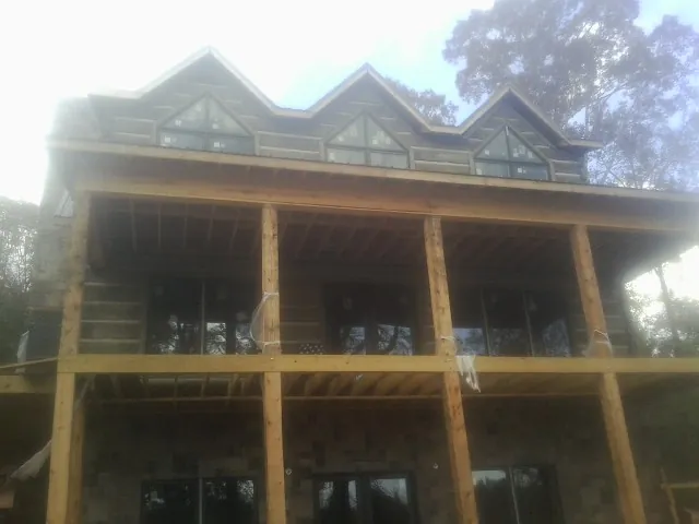 Dormers and porch framing on a large log home under construction — Roof Coating work by our crew in Waubun