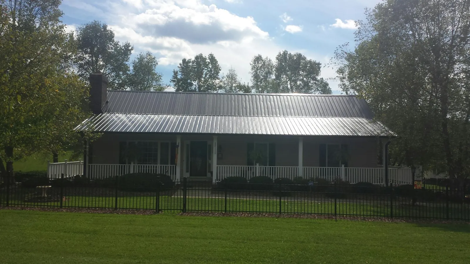 Gray metal roof on a brick ranch with a full width front porch — Gutter Guard Installation work by our crew in Waubun