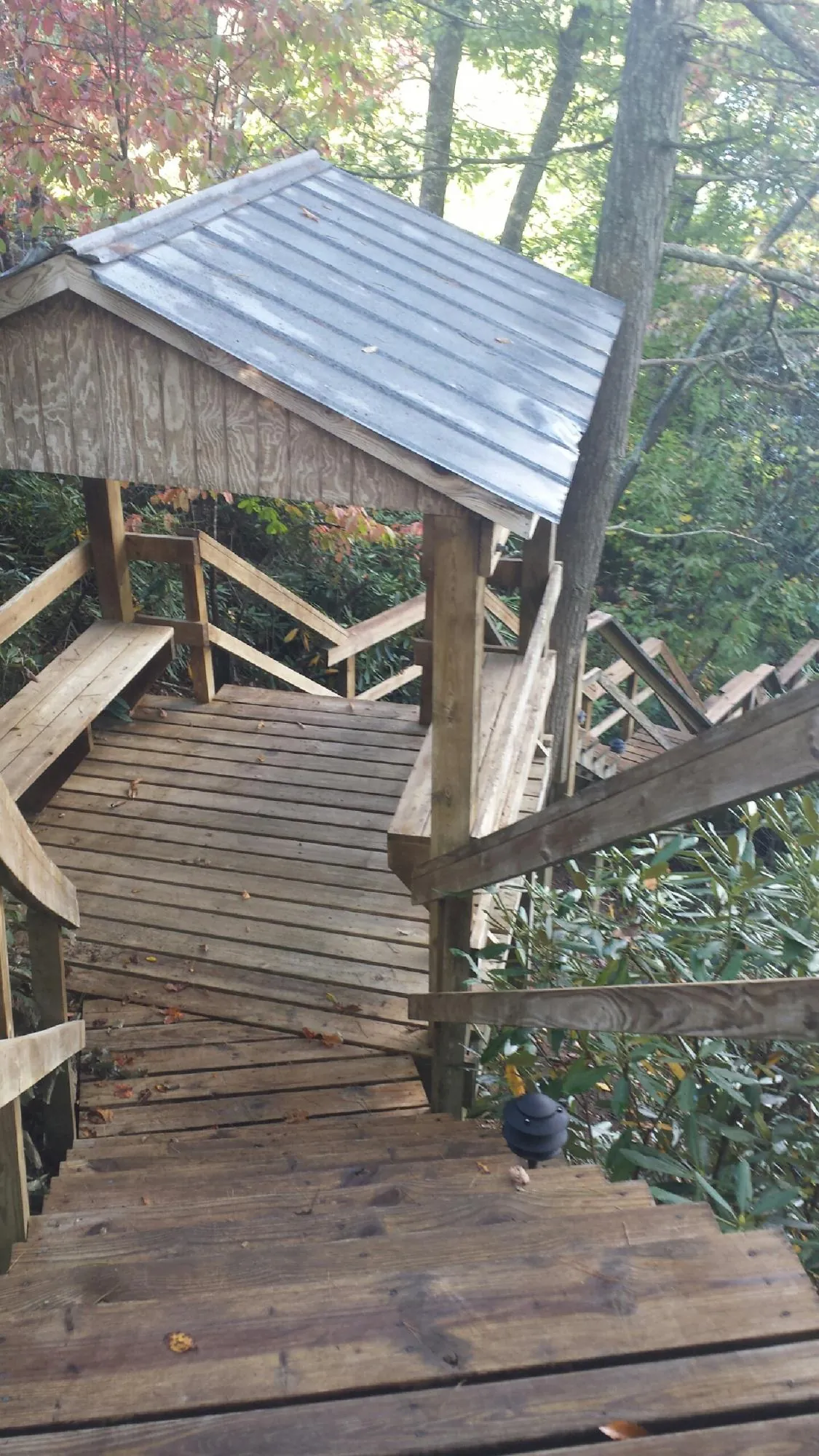 Metal roofed shelter over wooden steps on a wooded walkway — Skylight Repair & Installation work by our crew in Waubun