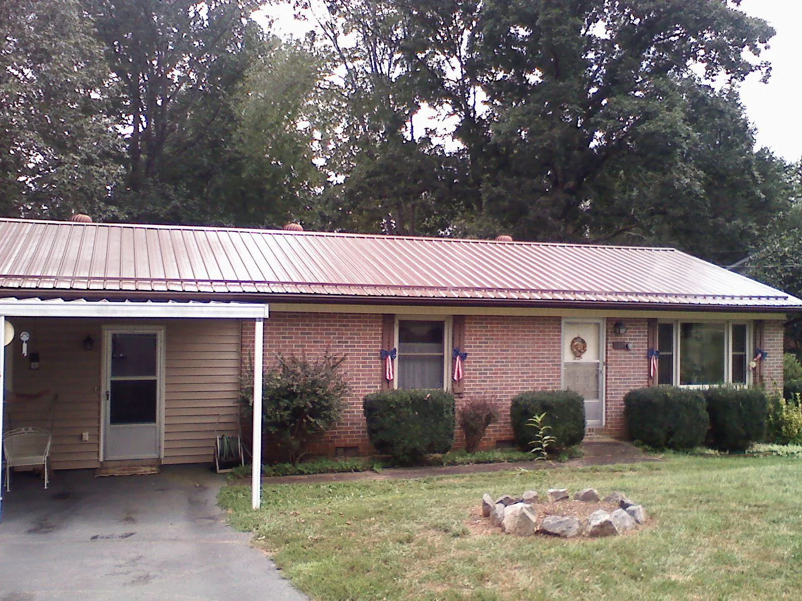 Bronze metal roof and carport on a brick ranch home — Roof Repair work by our crew in Waubun